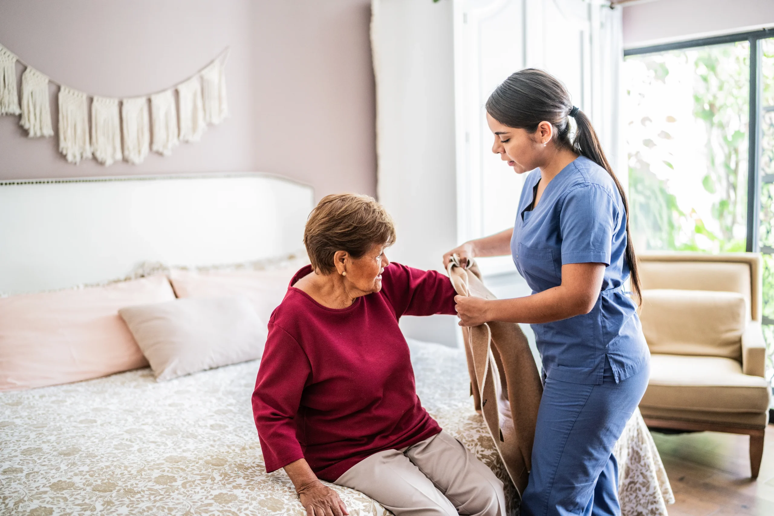 Caregiver putting coat on senior woman